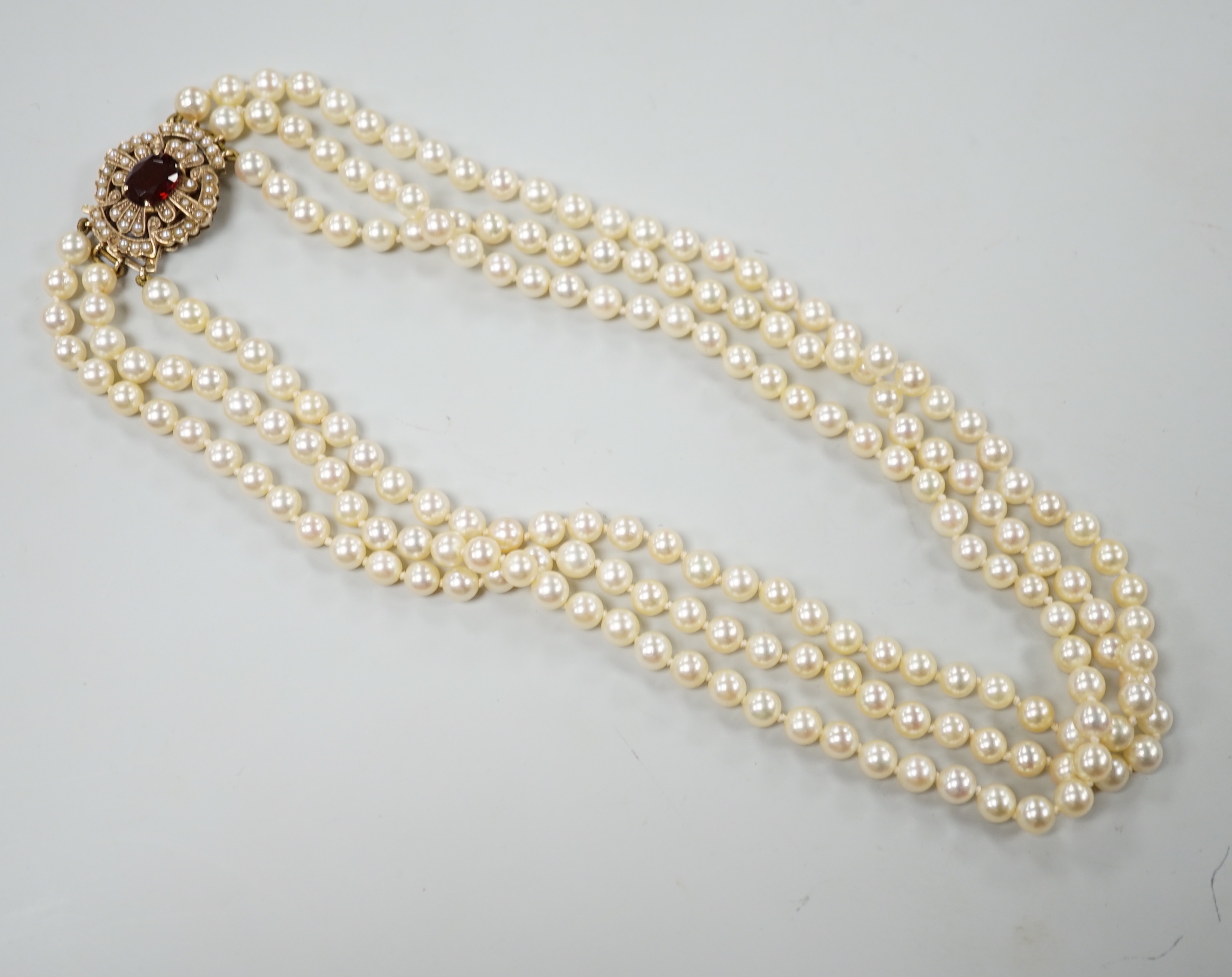 A 1960's triple strand cultured pearl choker necklace by Cropp & Farr, with 9ct gold, garnet and seed pearl set clasp, 39cm.